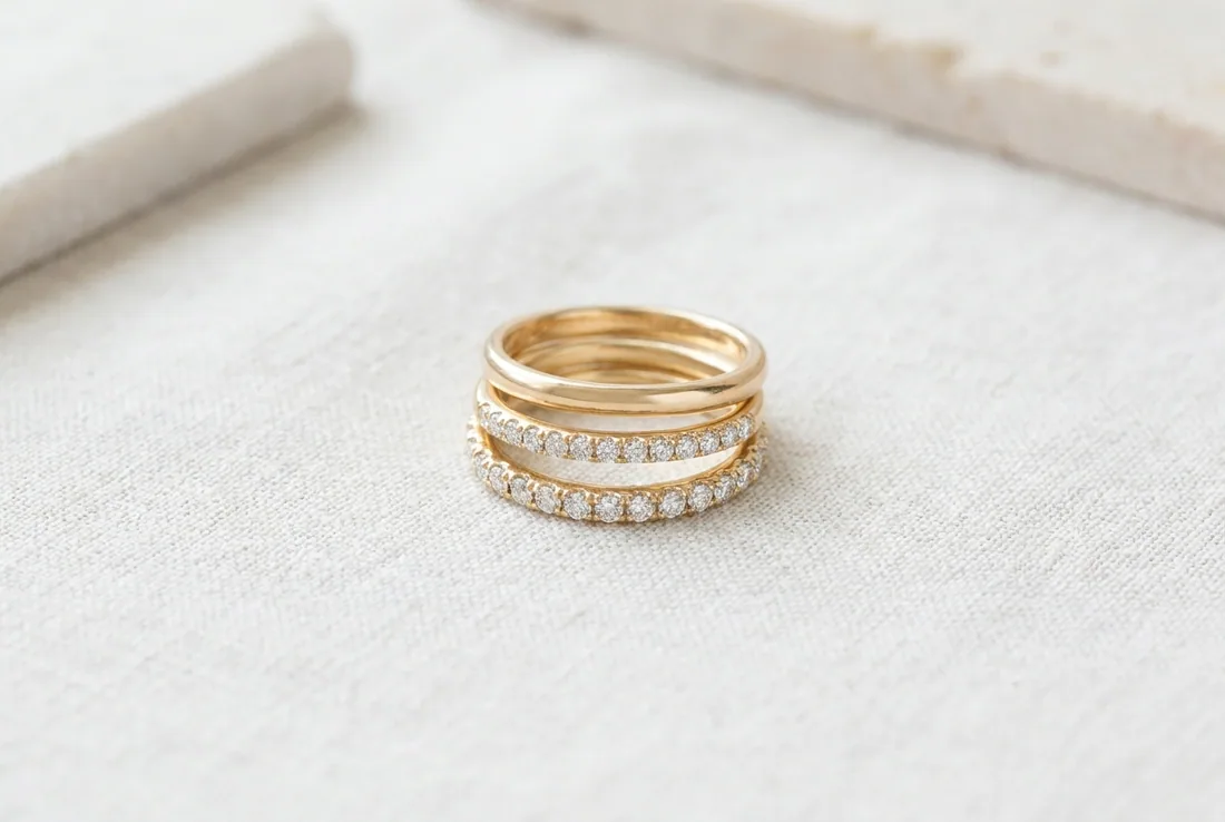 A plain gold wedding band beside half and full eternity rings on pale linen